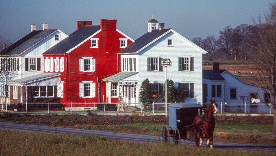 Buggy passes in front of an extended Amish family home, or dawdy haus, in Lancaster, PA. Photographing the Amish ©Blair Seitz