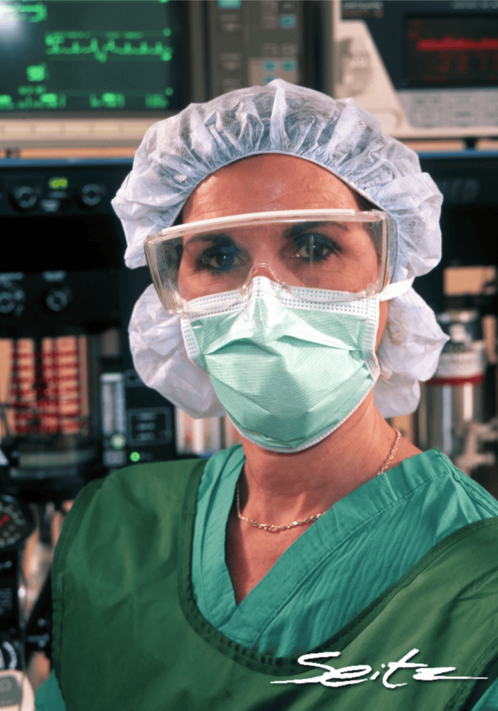Woman medical worker looks at the camera in mask and scrubs. © Blair Seitz